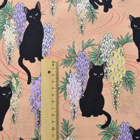 Le Tissu popeline coton imprimé floral chat de Longan Craft France représente des chats noirs avec des glycines violettes et blanches sur des pêches, présentés avec une règle en bois pour l'échelle. Idéal pour le bricolage, le patchwork, les robes, les chemises, ou la décoration intérieure.