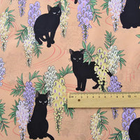 Le Tissu popeline coton imprimé floral chat au mètre de Longan Craft France représente des chats noirs parmi des glycines violettes sur un fond pêche - parfait pour le bricolage, le patchwork, les peignoirs, les chemises et la décoration intérieure.