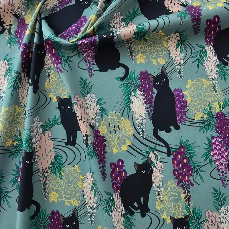 Longan Craft France Tissu popeline coton imprimé floral chat au mètre : tissu stretch orné de chats noirs et fleurs colorées sur fond teal, idéal pour DIY, patchwork, décoration intérieure, robes et chemises.