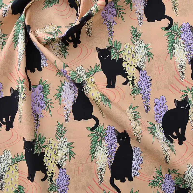 Tissu popeline coton stretch imprimé floral chat Longan Craft France au mètre, idéal pour DIY, patchwork, robes et chemises. Motifs chats noirs parmi glycines violettes/jaunes sur fond beige clair ; légères ondulations par endroits.