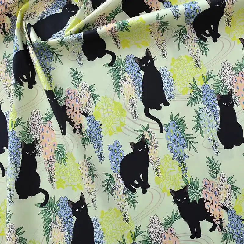 Longan Craft France Tissu popeline coton imprimé floral chat : tissu au mètre avec motifs de chats noirs et fleurs pastel sur fond vert clair, parfait pour DIY, patchwork, robes, chemises ou décoration intérieure.