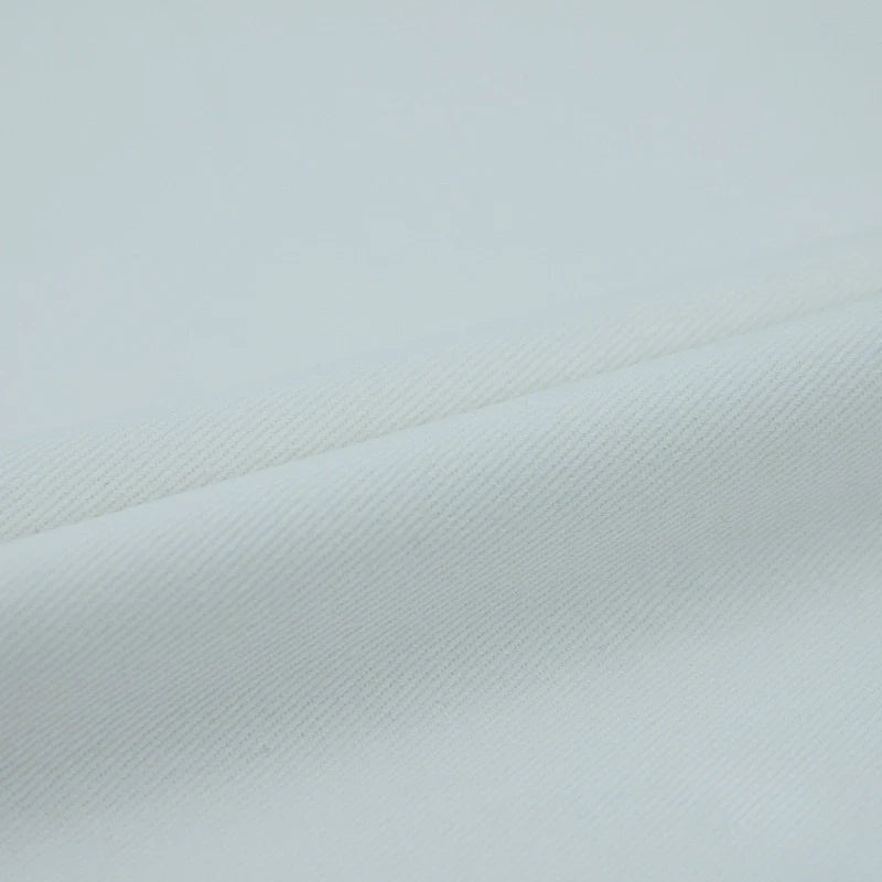 Gros plan sur le Tissu jean coloré 7,5 oz au mètre de Longan Craft France, un denim doux et léger 100% coton sergé multicolore pour jeans, montrant sa texture douce et son tissage subtil en diagonale avec de légers plis.