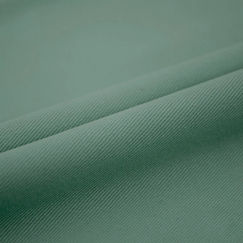 Gros plan sur le Tissu jean coloré 7,5 oz au mètre de Longan Craft France, un denim 100% coton sergé multicolore pour les jeans colorés, présentant un tissu vert clair avec une texture subtile de côtes diagonales et un fin détail de tissage.