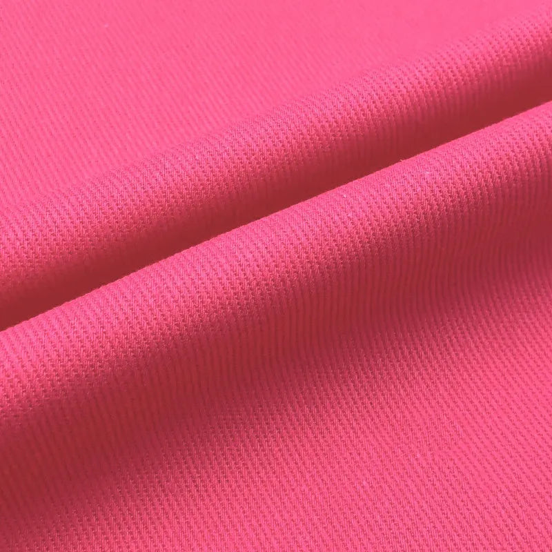 Gros plan sur le Tissu jean coloré 7,5 oz au mètre de Longan Craft France, un denim 100% coton sergé avec des plis diagonaux visibles, mettant en valeur la texture et le tissage - parfait pour des jeans colorés ou des projets décoratifs.