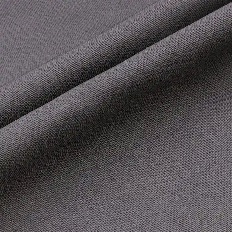 Un gros plan du Tissu jean coloré 7,5 oz au mètre de Longan Craft France montre son tissage sergé multicolore 100 % coton, avec des lignes diagonales et une texture lisse. Le denim de haute qualité est légèrement plié, ce qui crée des ombres douces.