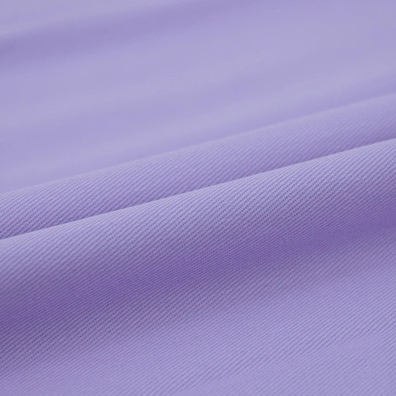 Gros plan sur le Tissu jean coloré 7,5 oz au mètre de Longan Craft France : denim 100% coton sergé multicolore avec une surface lisse et une texture nervurée en diagonale, idéal pour les vêtements et la décoration, avec des plis élégants et des ombres douces.