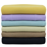 Une pile de six Tissu jean coloré 7,5 oz au mètre par Longan Craft France en jaune, lavande, bleu, vert, tan, et noir est soigneusement arrangée sur un fond blanc. Denim sergé multicolore 100% coton pour jeans colorés.