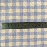 Une règle métallique (0-15 cm) est placée horizontalement sur la flanelle de coton à carreaux colorés au mètre de Longon Craft France, un tissu flanelle 100 % coton idéal pour les manteaux d'automne, les chemises, la couture et l'ameublement.