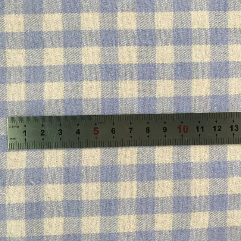 Une règle métallique (0-15 cm) est placée horizontalement sur la flanelle de coton à carreaux colorés au mètre de Longon Craft France, un tissu flanelle 100 % coton idéal pour les manteaux d'automne, les chemises, la couture et l'ameublement.