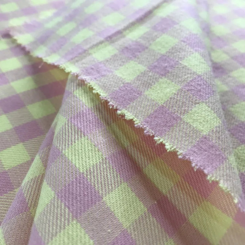 Gros plan sur la Flanelle de coton à carreaux colorés au mètre de Longon Craft France, à carreaux vichy rose et vert clair. Le bord est rosé en zigzag ; ce tissu 100% coton est idéal pour les manteaux, les chemises, la couture ou l'ameublement.