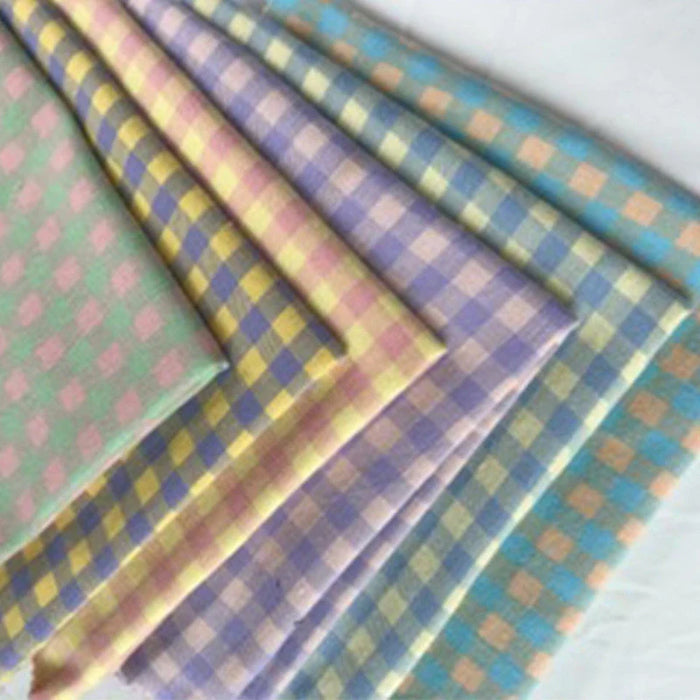 Plusieurs coupons de flanelle de coton à carreaux colorés Longon Craft France, parfaits pour pyjamas ou chemises, présentent des motifs verts, jaunes, violets, roses et bleus superposés sur fond blanc.