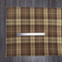 Le tissu en flanelle à carreaux colorés de Longon Craft France, doux et parfait pour l'automne, est posé sur une table sombre avec une règle en métal de 20 cm pour illustrer sa matière polyester-coton ultra-douillette.