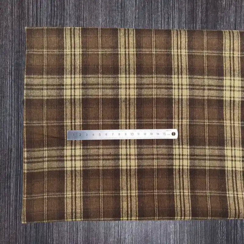 Le tissu en flanelle à carreaux colorés de Longon Craft France, doux et parfait pour l'automne, est posé sur une table sombre avec une règle en métal de 20 cm pour illustrer sa matière polyester-coton ultra-douillette.