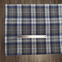 Un morceau de tissu en flanelle à carreaux colorés au mètre de Longon Craft France est posé sur une surface en bois, avec une règle métallique de 20 cm placée horizontalement sur le tissu polyester-coton ultra-douillet.