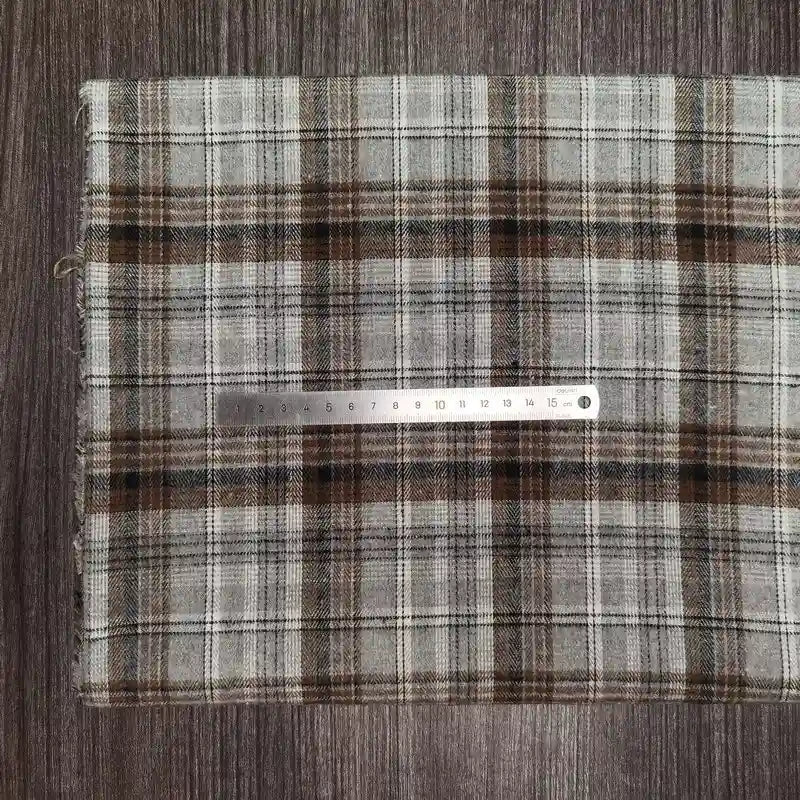A folded Tissu en flanelle à carreaux colorés Longon Craft France, ultra-douillette polyester-coton pour l'automne, repose sur un bois sombre avec une règle métallique de 20 cm posée dessus, parfait pour vêtements d'hiver.