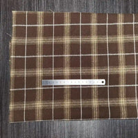 A Tissu en flanelle à carreaux colorés Longon Craft France, polyester-coton ultra-douillet, est posé sur du bois sombre. Une règle métallique de 20 cm repose horizontalement sur cette matière confortable pour l'automne.
