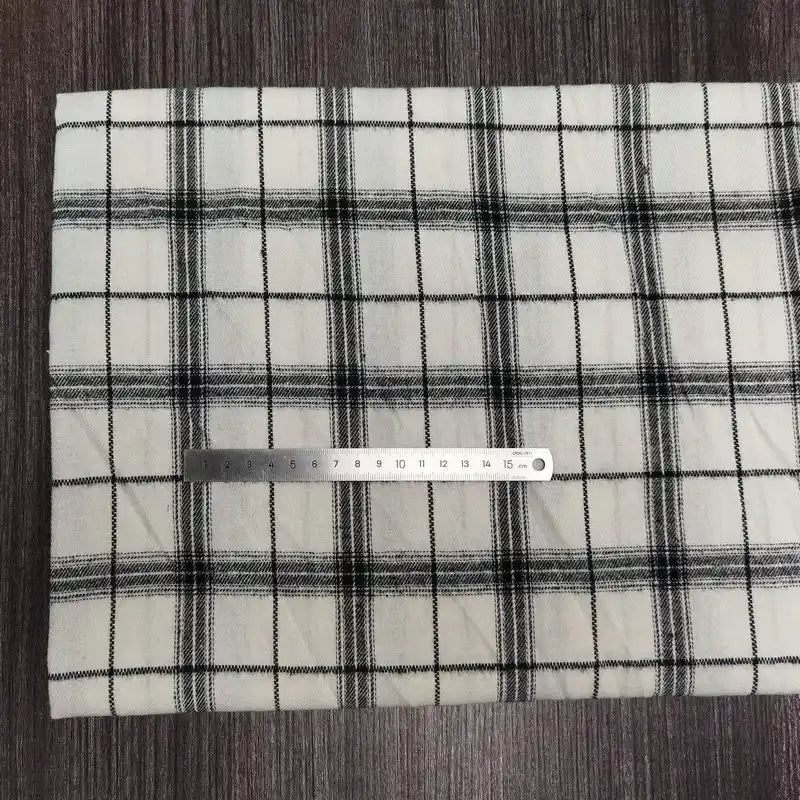A mètre of Tissu en flanelle à carreaux colorés by Longon Craft France, une flanelle polyester-coton ultra-douillette idéale pour l'automne, est présenté avec une règle de 20 cm sur un fond en bois.