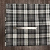 Un morceau de tissu en flanelle à carreaux colorés au mètre de Longon Craft France est posé à plat, avec une règle métallique de 20 cm en travers pour montrer l'échelle. Ce tissu en polyester-coton est ultra-douillet et parfait pour l'automne.
