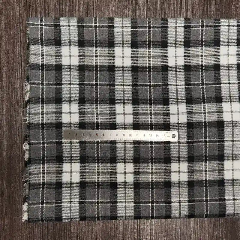 Un morceau de tissu en flanelle à carreaux colorés au mètre de Longon Craft France est posé à plat, avec une règle métallique de 20 cm en travers pour montrer l'échelle. Ce tissu en polyester-coton est ultra-douillet et parfait pour l'automne.