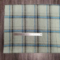 A piece of Tissu en flanelle à carreaux colorés Longon Craft France, doux polyester-coton pour l'automne, is posé à plat avec une règle métallique en centimètres sur le tissu pour indiquer l'échelle.
