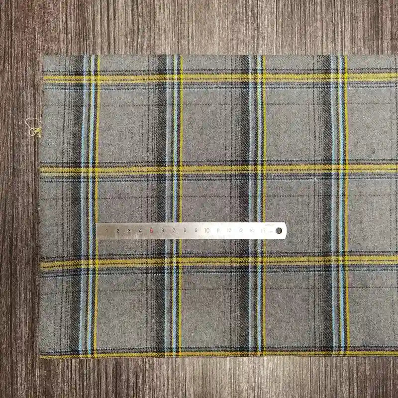 A piece of Longon Craft France Tissu en flanelle à carreaux colorés au mètre, une matière polyester-coton ultra-douillette pour l'automne, is posé sur du bois avec une règle métallique de 30 cm placée dessus horizontalement.