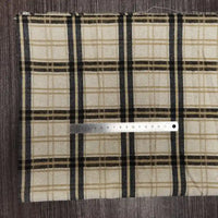 A Longon Craft France tissu en flanelle à carreaux colorés au mètre, ultra-douillette, repose sur du bois. Une règle argentée de 15 cm est placée horizontalement près du bas du tissu.