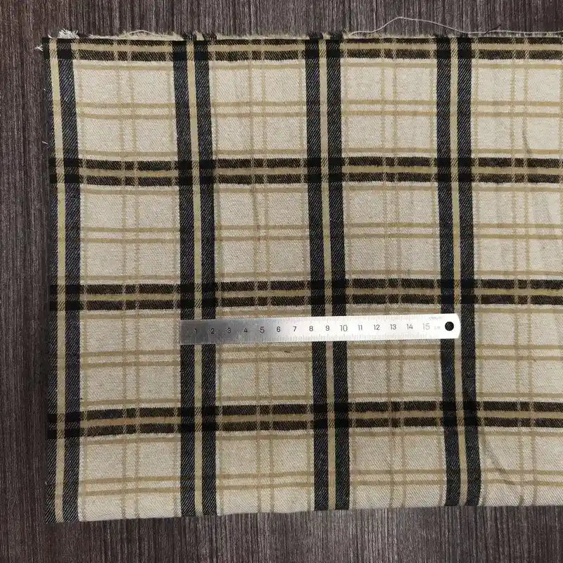 A Longon Craft France tissu en flanelle à carreaux colorés au mètre, ultra-douillette, repose sur du bois. Une règle argentée de 15 cm est placée horizontalement près du bas du tissu.