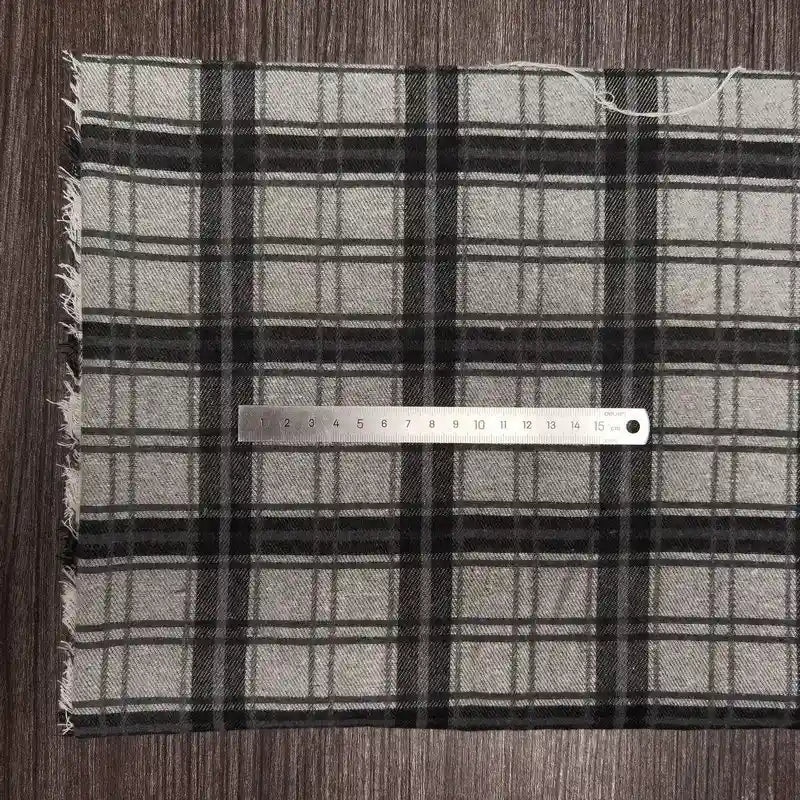 Un morceau de tissu en flanelle à carreaux colorés au mètre, polyester-coton ultra-douillet pour l'automne, de Longon Craft France, est présenté sur du bois avec une règle métallique de 20 cm placée horizontalement pour l'échelle.