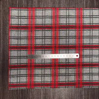 Un coupon de tissu en flanelle à carreaux colorés Longon Craft France, matière polyester-coton ultra-douillette pour l'automne, est posé sur une table sombre avec une règle métallique de 15 cm placée horizontalement dessus.