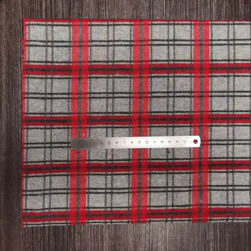 Un coupon de tissu en flanelle à carreaux colorés Longon Craft France, matière polyester-coton ultra-douillette pour l'automne, est posé sur une table sombre avec une règle métallique de 15 cm placée horizontalement dessus.
