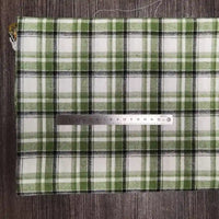 Un morceau de Tissu en flanelle à carreaux colorés au mètre de Longon Craft France, une flanelle polyester-coton ultra-douillette pour l'automne, repose sur une surface grise avec une règle argentée de 20 cm posée dessus.