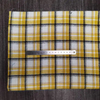 Une flanelle à carreaux jaune, blanche et noire de Longon Craft France est posée à plat sur du gris. Une règle métallique de 15 cm indique l'échelle de ce tissu en flanelle polyester-coton ultra-douillette, idéal pour vêtements d'automne et d'hiver.