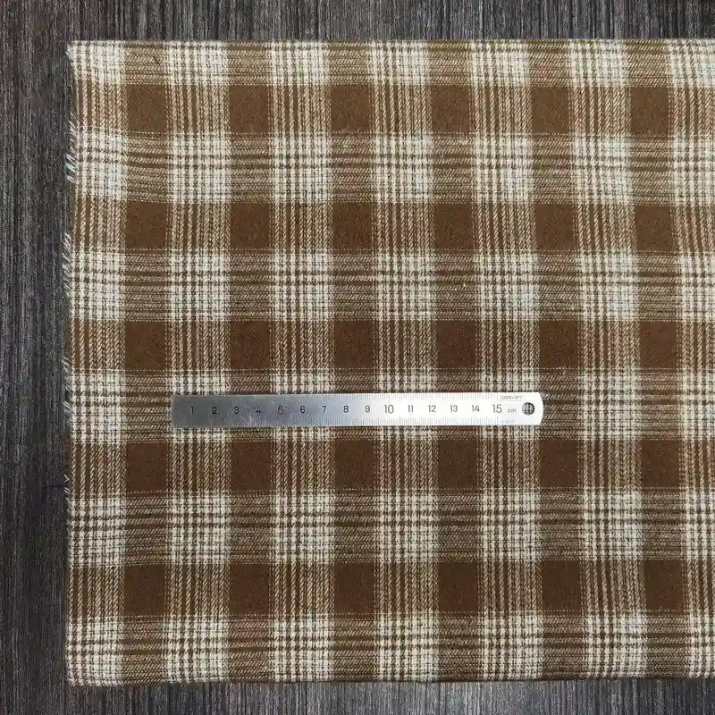 Une règle en métal est posée sur Tissu en flanelle à carreaux colorés de Longon Craft France, mesurant 18 cm pour montrer l'échelle de ce tissu d'ameublement en polyester-coton, une matière ultra-douce parfaite pour l'automne.
