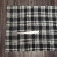 A piece of Tissu en flanelle à carreaux colorés au mètre de Longon Craft France, matière polyester-coton ultra-douillette, is posé à plat sur du bois sombre avec une règle métallique de 20 cm placée horizontalement dessus.