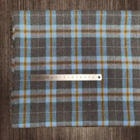 A Longon Craft France metal ruler lies on Tissu en flanelle à carreaux colorés au mètre, une flanelle polyester-coton ultra-douillette idéale pour l'automne, parfait comme tissu pour vêtements d'hiver. La règle indique les centimètres.
