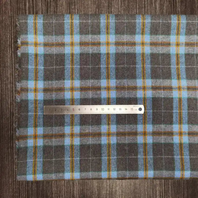 A Longon Craft France metal ruler lies on Tissu en flanelle à carreaux colorés au mètre, une flanelle polyester-coton ultra-douillette idéale pour l'automne, parfait comme tissu pour vêtements d'hiver. La règle indique les centimètres.