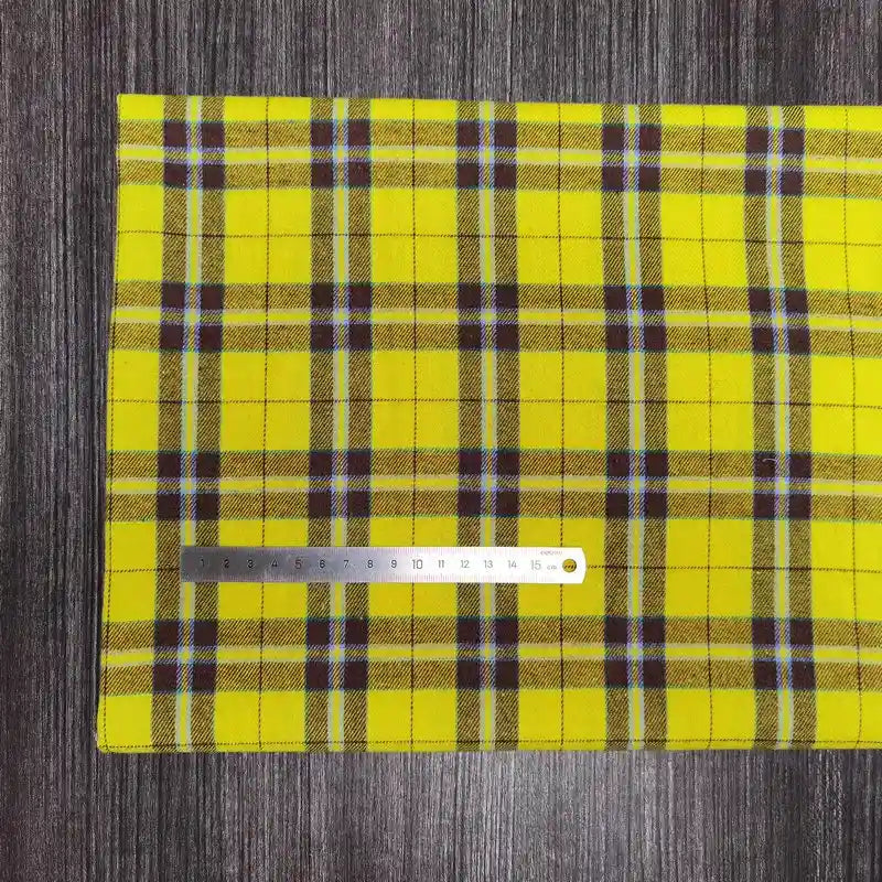Un tissu en flanelle à carreaux colorés Longon Craft France, polyester-coton ultra-douillet pour l'automne, est posé sur un bois foncé. Une règle argentée de 20 cm est placée horizontalement sur le tissu pour l'échelle.