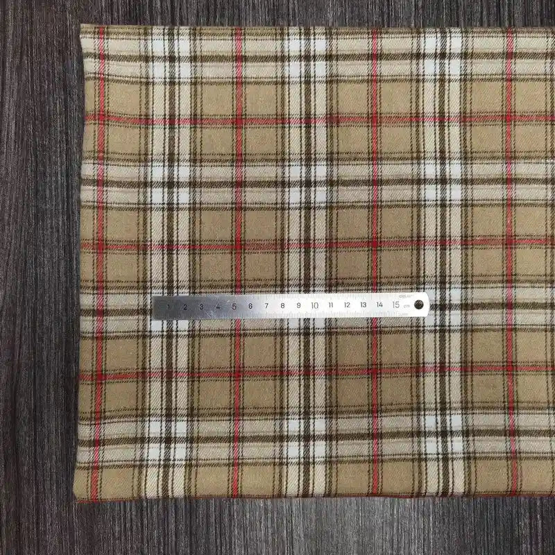 Un morceau de Tissu en flanelle à carreaux colorés Longon Craft France, polyester-coton ultra-douillet, est posé à plat sur du bois foncé avec une règle de 15 cm, parfait pour vêtements d'automne ou hiver.