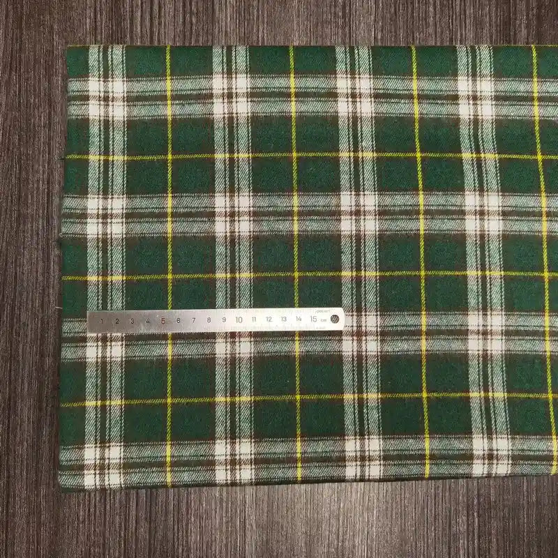 Le Tissu en flanelle à carreaux colorés au mètre de Longon Craft France, une flanelle polyester-coton ultra-douillette, est étalé sur du bois sombre. Une règle métallique indique environ 20 cm de tissu.