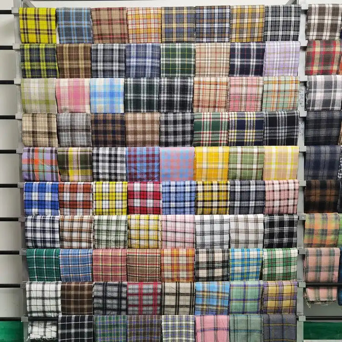 Un présentoir met en valeur le tissu en flanelle à carreaux colorés au mètre de Longon Craft France, une matière polyester-coton ultra-douillette idéale pour l'automne et les vêtements d'hiver, disponible en divers motifs et couleurs.