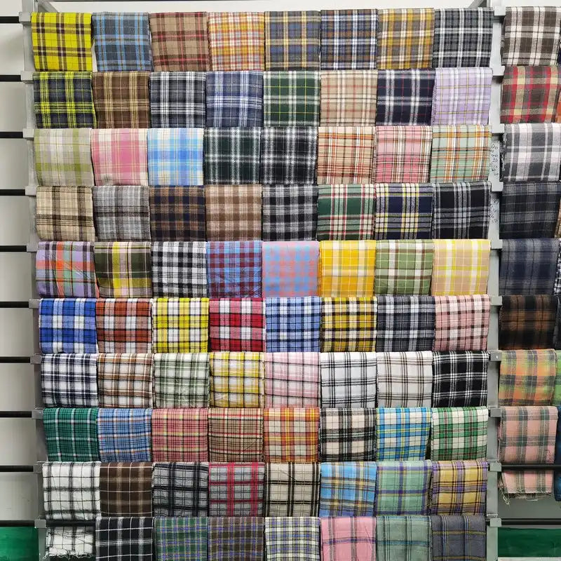 Un présentoir met en valeur le tissu en flanelle à carreaux colorés au mètre de Longon Craft France, une matière polyester-coton ultra-douillette idéale pour l'automne et les vêtements d'hiver, disponible en divers motifs et couleurs.