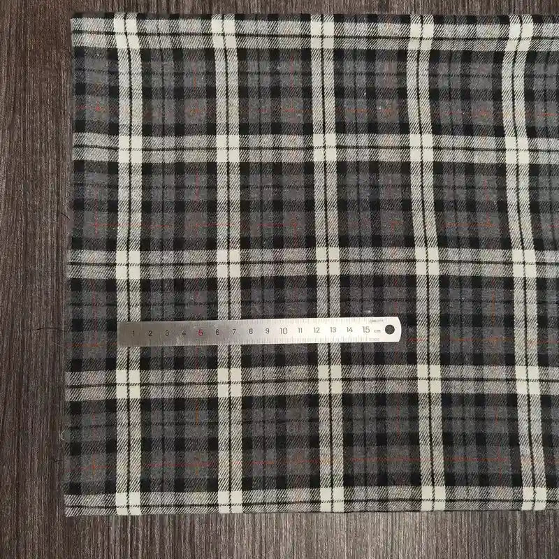 A tissu en flanelle à carreaux colorés Longon Craft France est posé sur une surface en bois foncé, avec une règle métallique graduée de 0 à 16 cm pour indiquer la taille du tissu ultra-douillet, idéal pour l'automne.