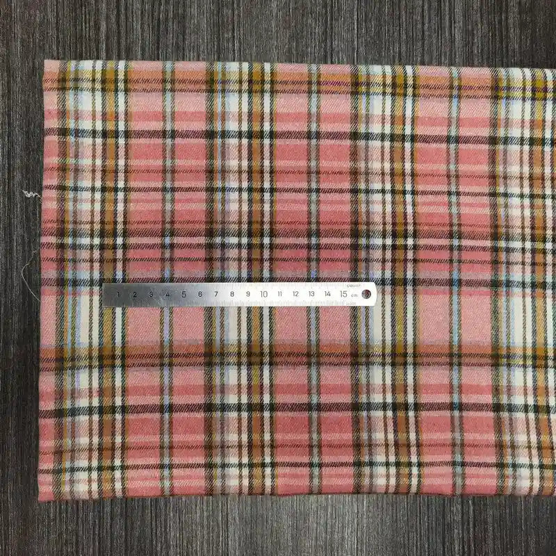 Un tissu en flanelle à carreaux colorés de Longon Craft France est posé sur une surface grise avec une règle métallique de 20 cm. Cette flanelle polyester-coton ultra-douillette est idéale pour l'automne et parfaite pour la confection de vêtements.