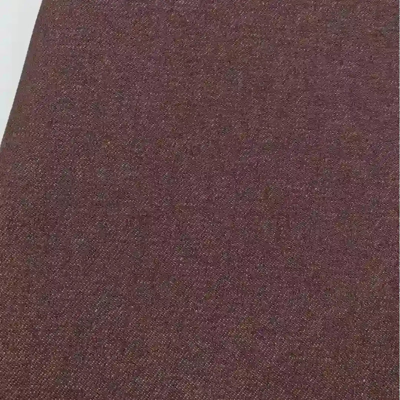 Un gros plan du tissu jean tissé coloré au mètre de Longan Craft France, un denim sergé teint 6,5 oz en coton, montre son motif subtil-idéal pour décoration intérieure ou confection de jeans.
