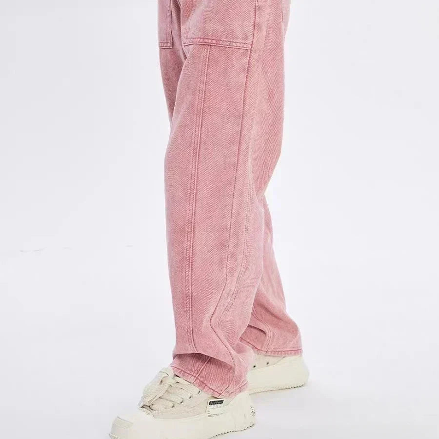 Une personne portant un jean rose ample en Tissu jean tissé coloré au mètre, Denim sergé teint 6,5 oz en coton de Longan Craft France, et des baskets blanches se tient debout sur un fond clair uni. Seule la partie inférieure du corps est représentée.
