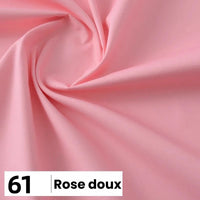 Gros plan sur une popeline de coton au mètre (Longan Craft France) rose pâle, douce et lisse, légèrement froncée. Une étiquette dans le coin indique "61 Rose doux" en gras noir sur blanc. Parfait pour les chemises, les robes ou les doublures.