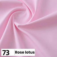 Gros plan sur une popeline de coton rose pâle et lisse de Longan Craft France, disposée en plis souples. Une étiquette en bas à gauche indique "73 Rose lotus" pour Popeline légère unie et douce, idéale pour les chemises, les robes et les doublures.