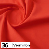Gros plan sur la popeline de coton au mètre de Longan Craft France en vermillon brillant, légèrement froncée au centre. En bas à gauche se trouve une étiquette blanche portant les mentions "36" et "Vermillon" en caractères noirs gras.