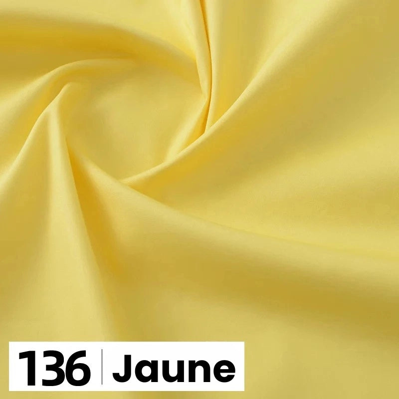 Un gros plan de popeline de coton jaune clair et lisse de Longan Craft France, étiquetée "136 Jaune" en bas à gauche, présente ce tissu doux et léger idéal pour les chemises, les robes, les doublures et d'autres projets de couture.