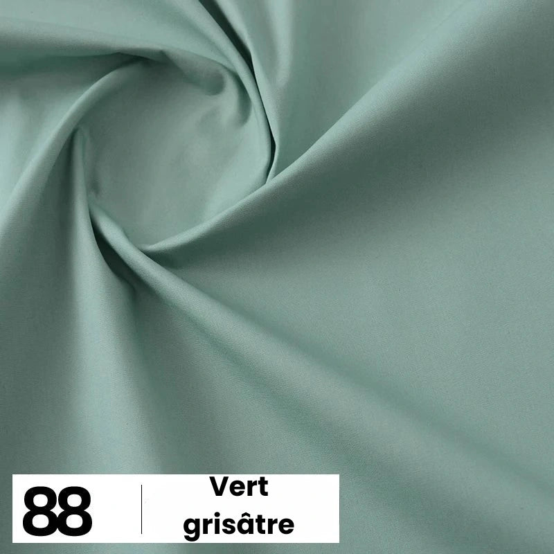 Un gros plan montre la Popeline de coton au mètre de Longan Craft France (88 Vert grisâtre), un tissu 100 % coton idéal pour les chemises, les robes et les doublures, avec un léger tourbillon et une étiquette indiquant le nom et le numéro de la couleur.